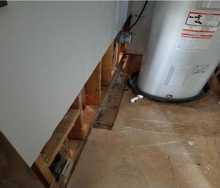 A utility room with baseboards and sheetrock removed near the hot water heater