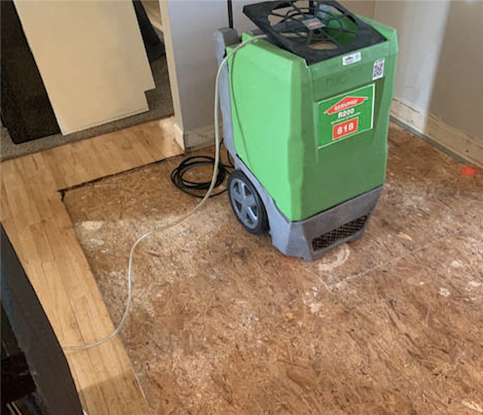 Large green piece of equipment sitting on a wood floor. 
