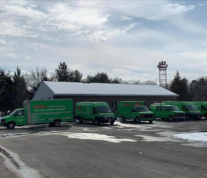 Fleet of vehicles in front of a building with a snowy roof.