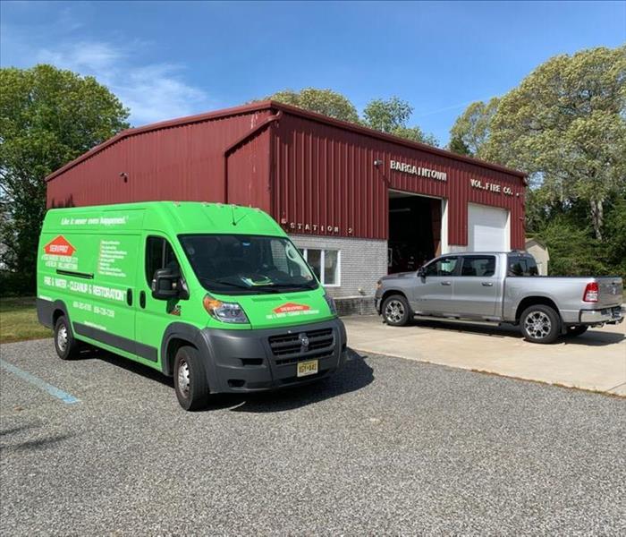 Green SERVPRO truck outside of a brown building. 
