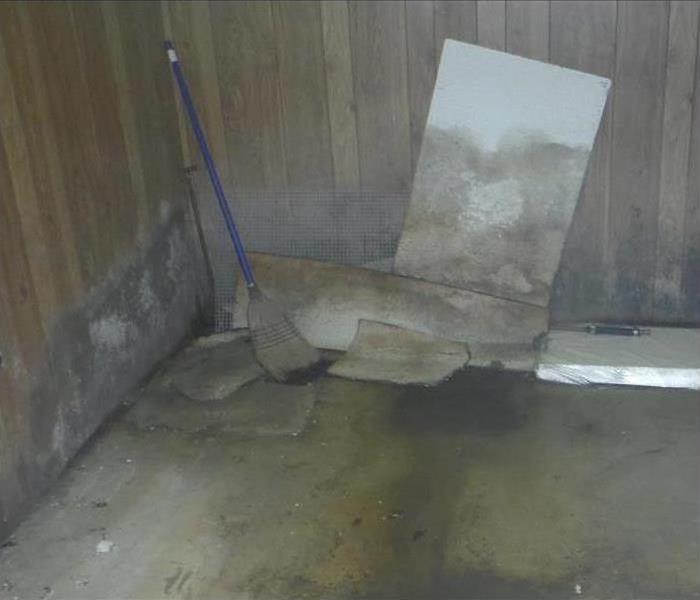 Picture of a wall, broom and pieces of drywall